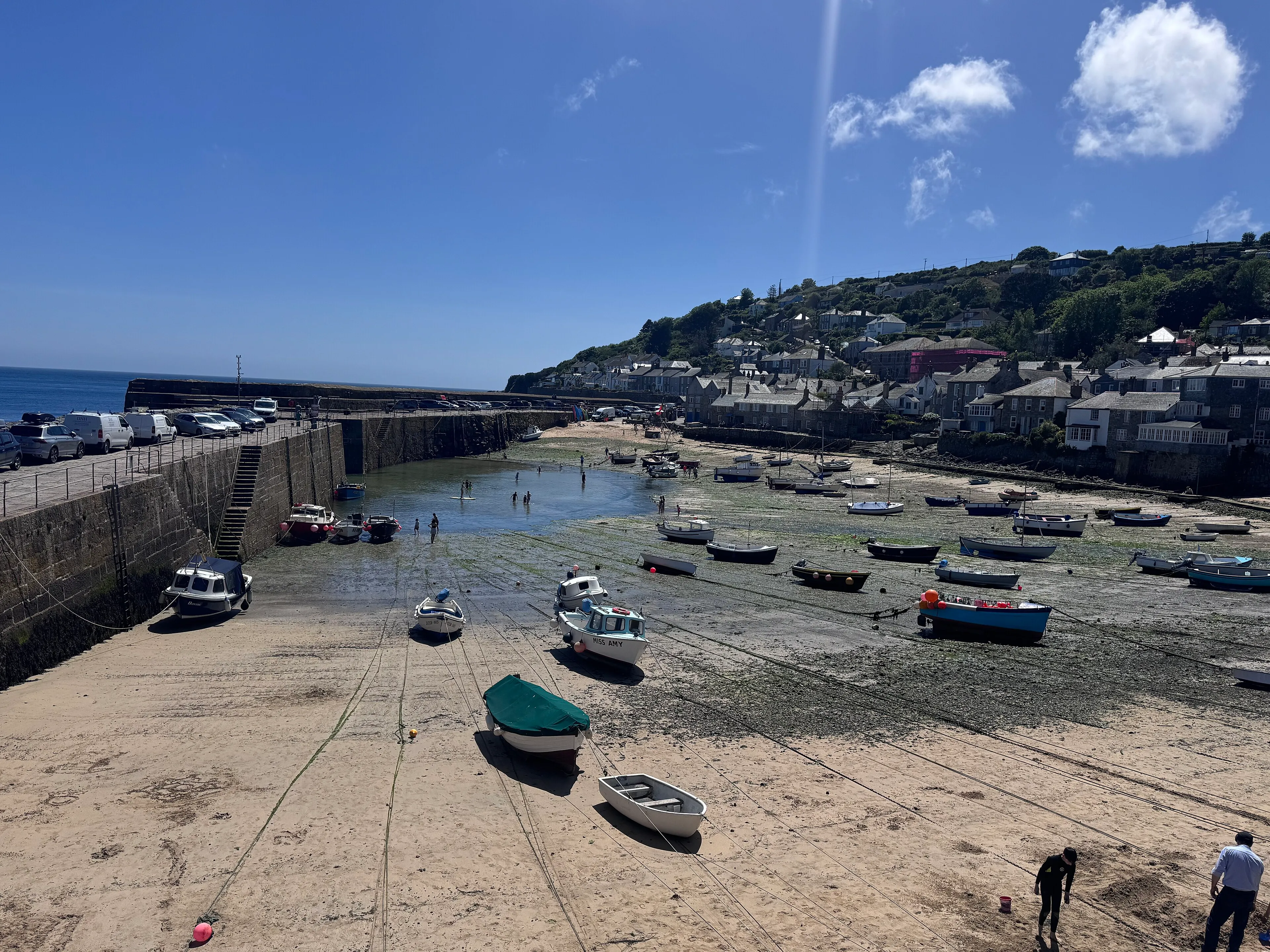 Small boats resting on the sand in Mousehole harbour at low tide